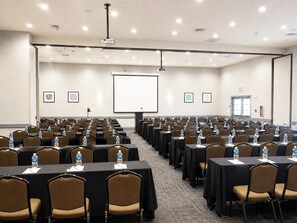 A conference room with rows of tables and chairs, a projector screen, and a presentation screen. - Holiday Inn Express San Clemente N – Beach Area by IHG (San Clemente)