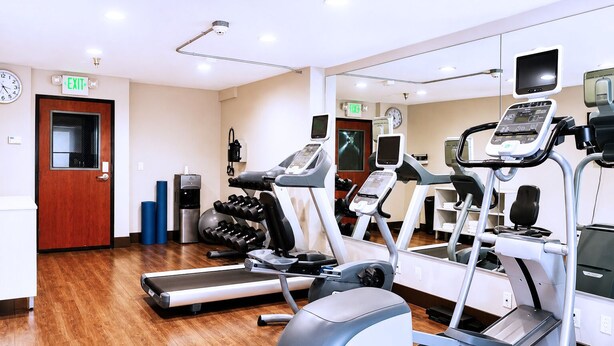 Ein Fitnessstudio mit Laufbändern, Crosstrainern und Kurzhanteln.
