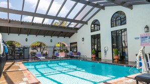A covered swimming pool with lounge chairs and potted plants. - Holiday Inn Express San Clemente N – Beach Area by IHG (San Clemente)
