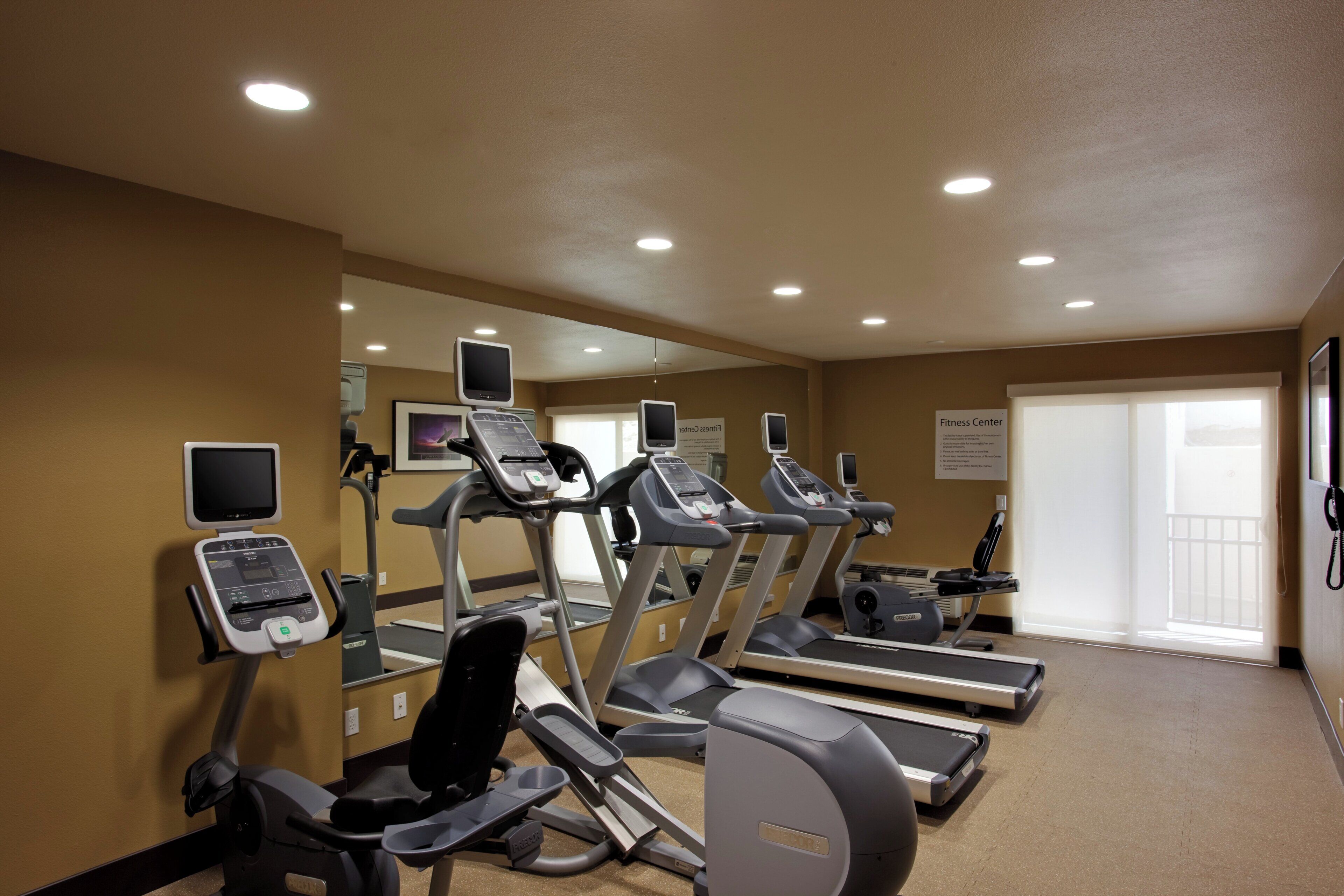A fitness center with treadmills, exercise bikes, and a mirrored wall.
