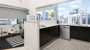 A modern kitchen with a city view, black cabinets, a white countertop, and a large window. - The Ridge Apartment Hotel (Spring Hill)
