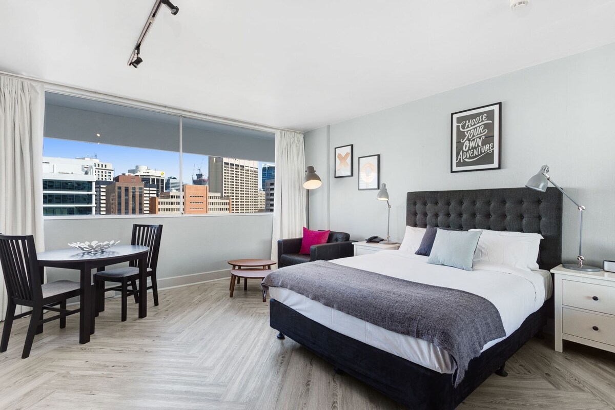 Een moderne hotelkamer met een groot bed, een bureau en uitzicht op de stad.