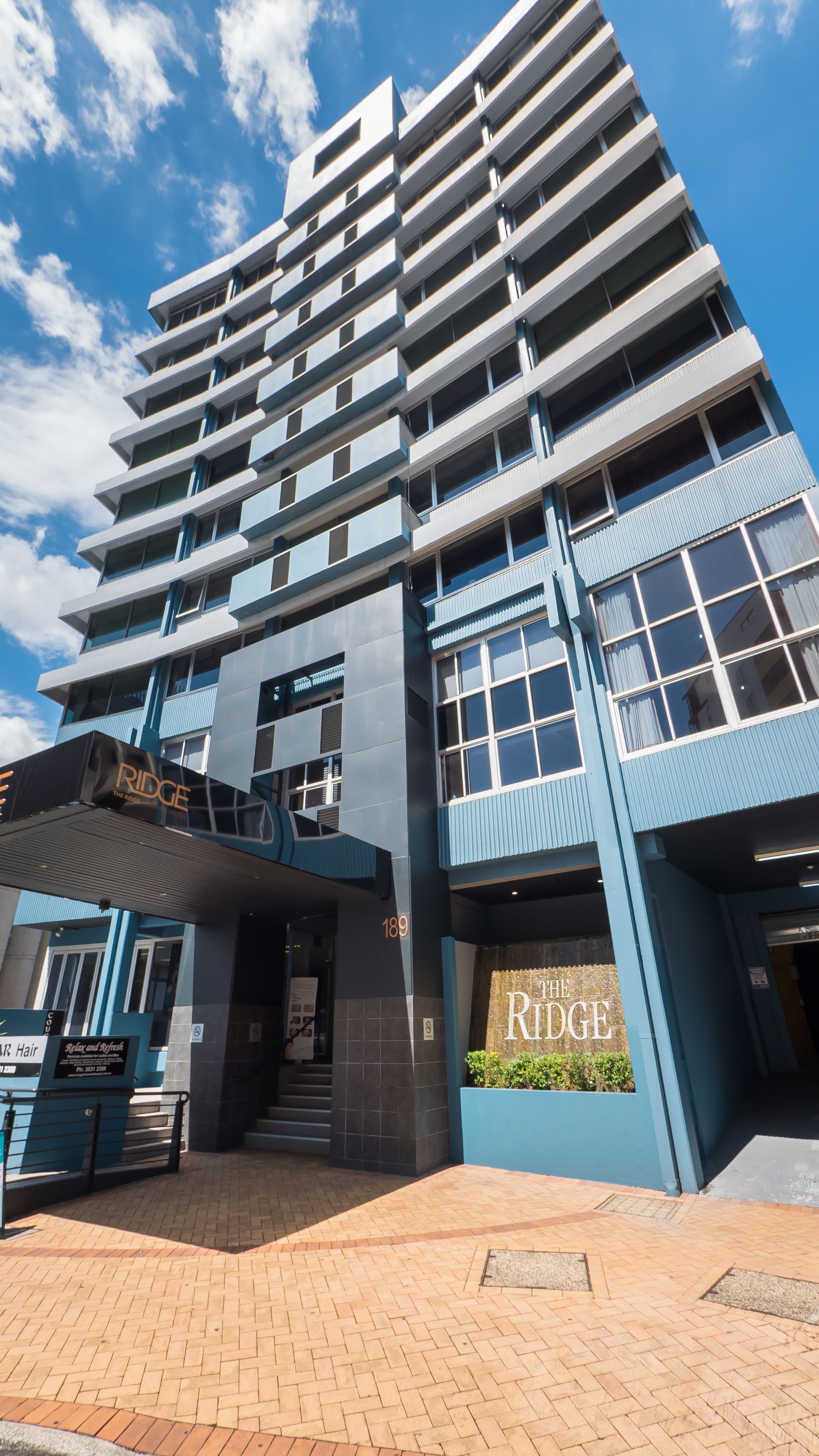 Un hotel moderno con una entrada destacada, varios balcones y un letrero que dice "The Ridge".
