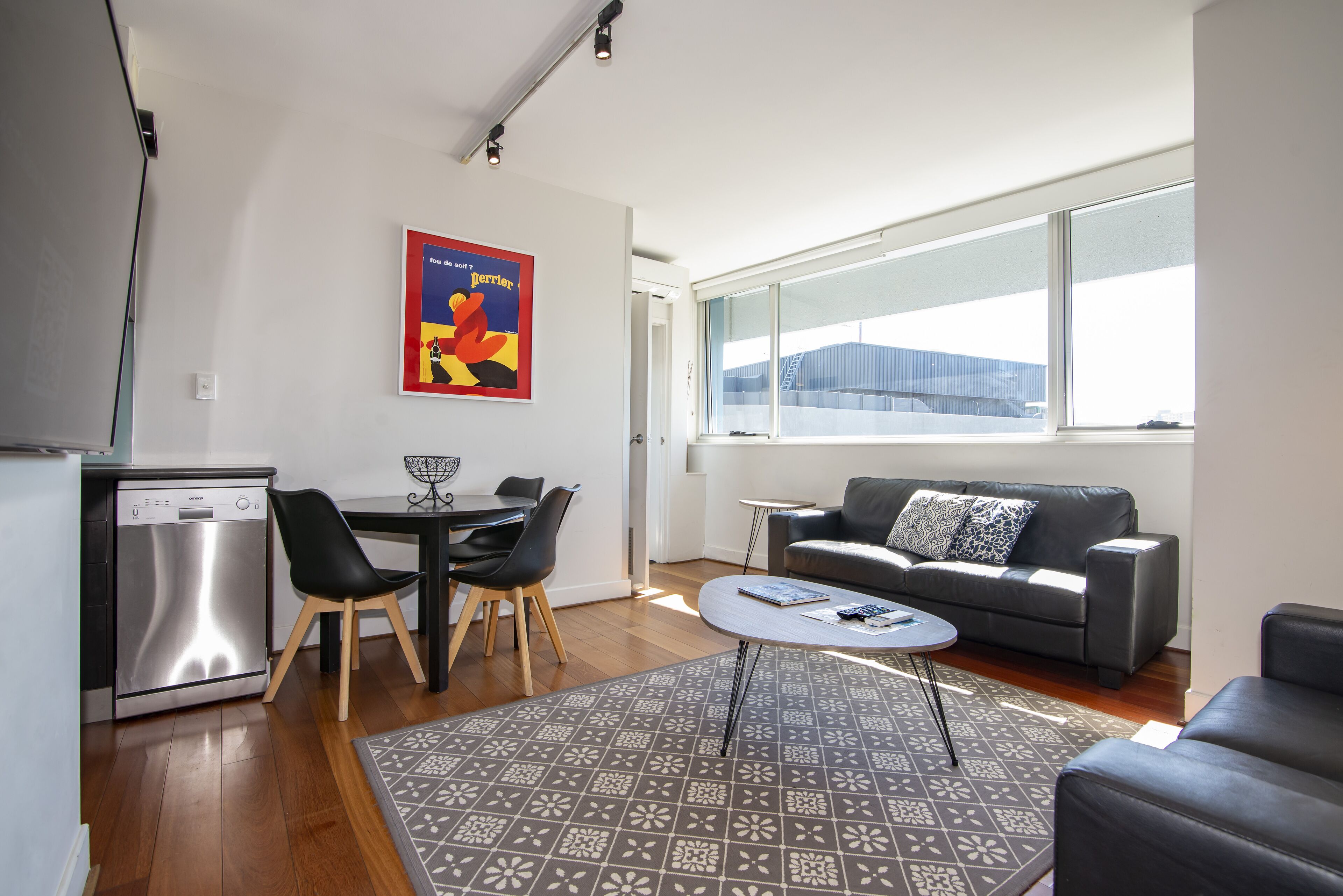 A modern living room with a sofa, coffee table, and a dining area with chairs and a table.