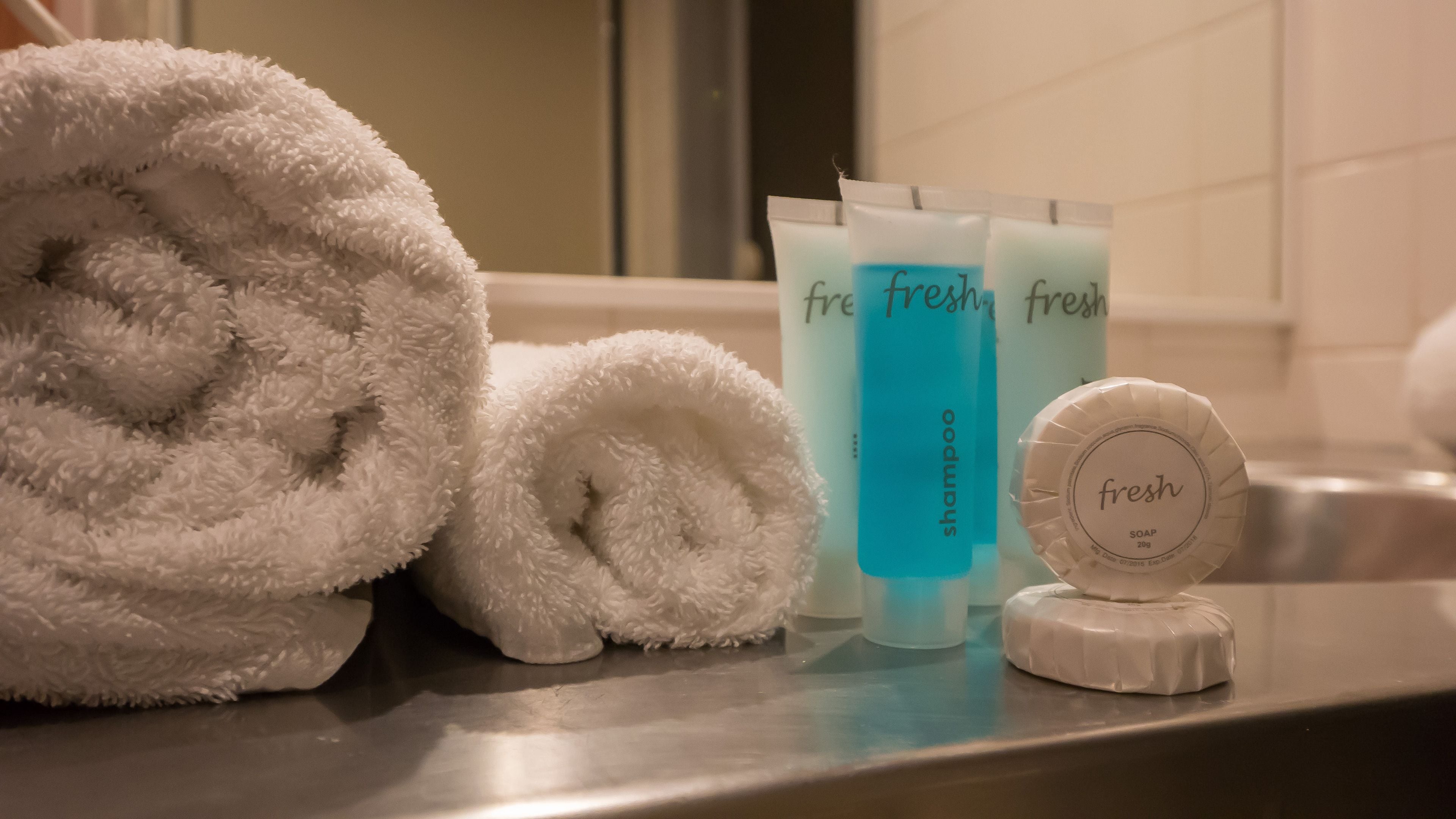 A bathroom with a towel, shampoo, and soap on the counter.