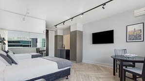 A modern bedroom with a large bed, a dining table, and a TV on the wall. - The Ridge Apartment Hotel (Spring Hill)