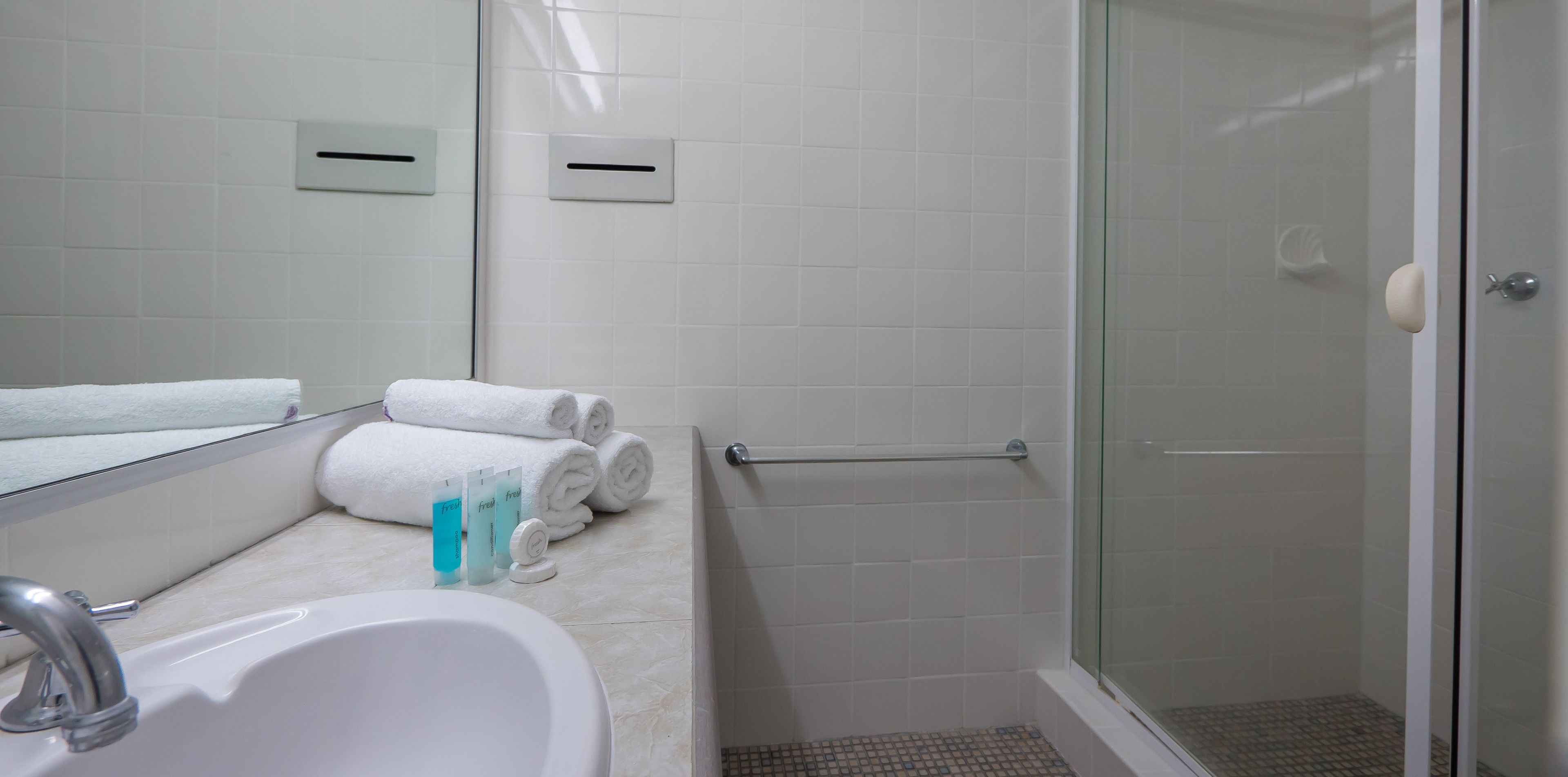 A bathroom with a sink, mirror, and glass-enclosed shower.