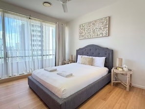 A bedroom with a large bed, a ceiling fan, a window with sheer curtains, and a wall-mounted artwork. - The Summit Apartments (Spring Hill)