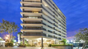 Un hôtel moderne à plusieurs étages, doté d’une façade sobre et d’une entrée bien éclairée.
