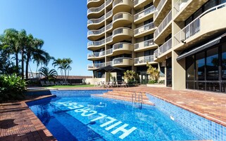 Ein Hotel mit Schwimmbad, Außenbereich und einem mehrstöckigen Gebäude mit Balkonen.