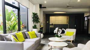 Un moderno vestíbulo con un sofá gris, dos sillones, una mesa de centro y un mostrador de recepción.