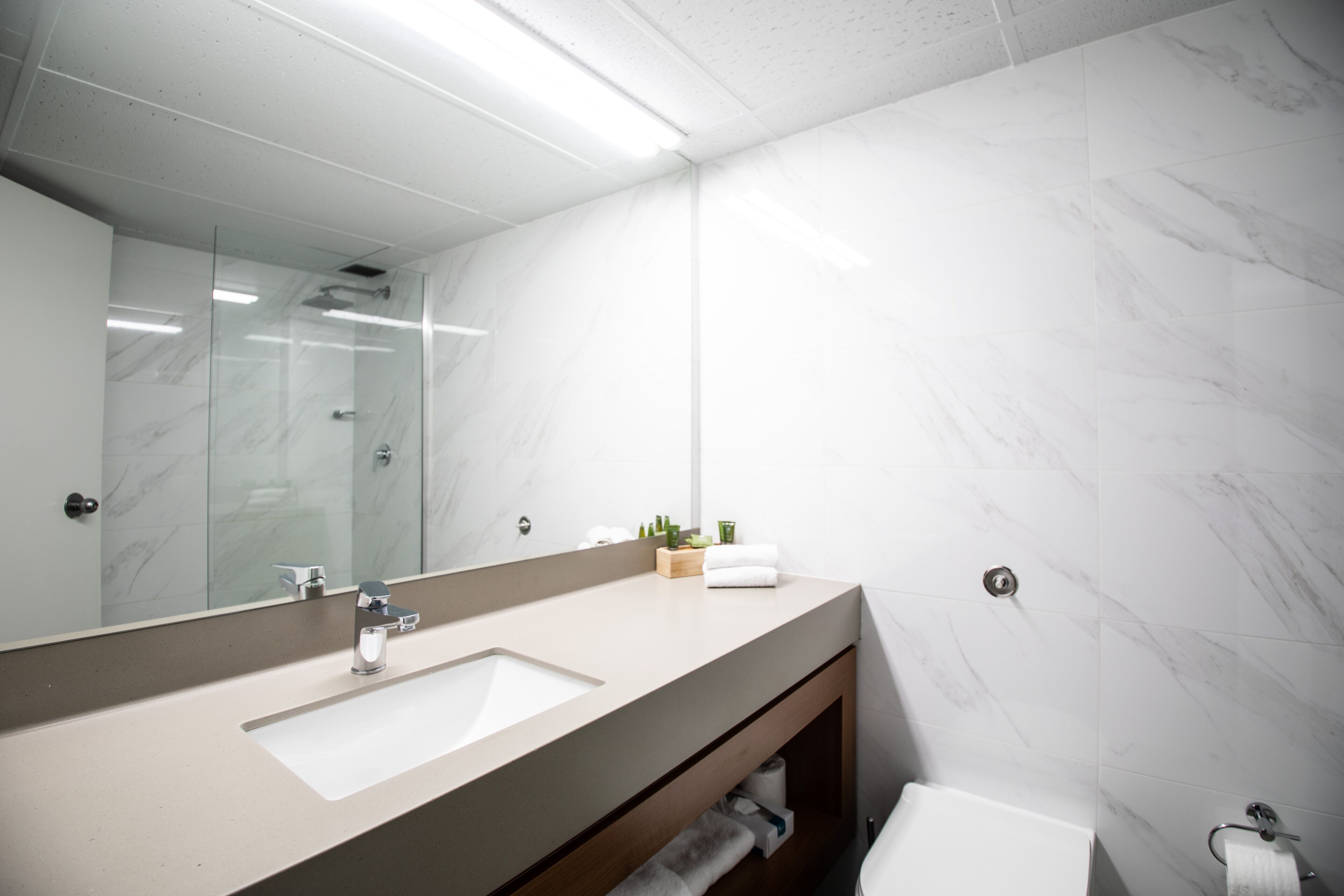 Un bagno moderno con uno specchio grande, due lavabi e un water.