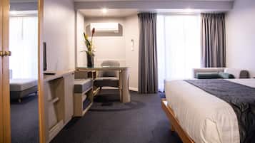 Een hotelkamer met een bed, een bureau met stoel, een bijzettafeltje en een kamerplant.