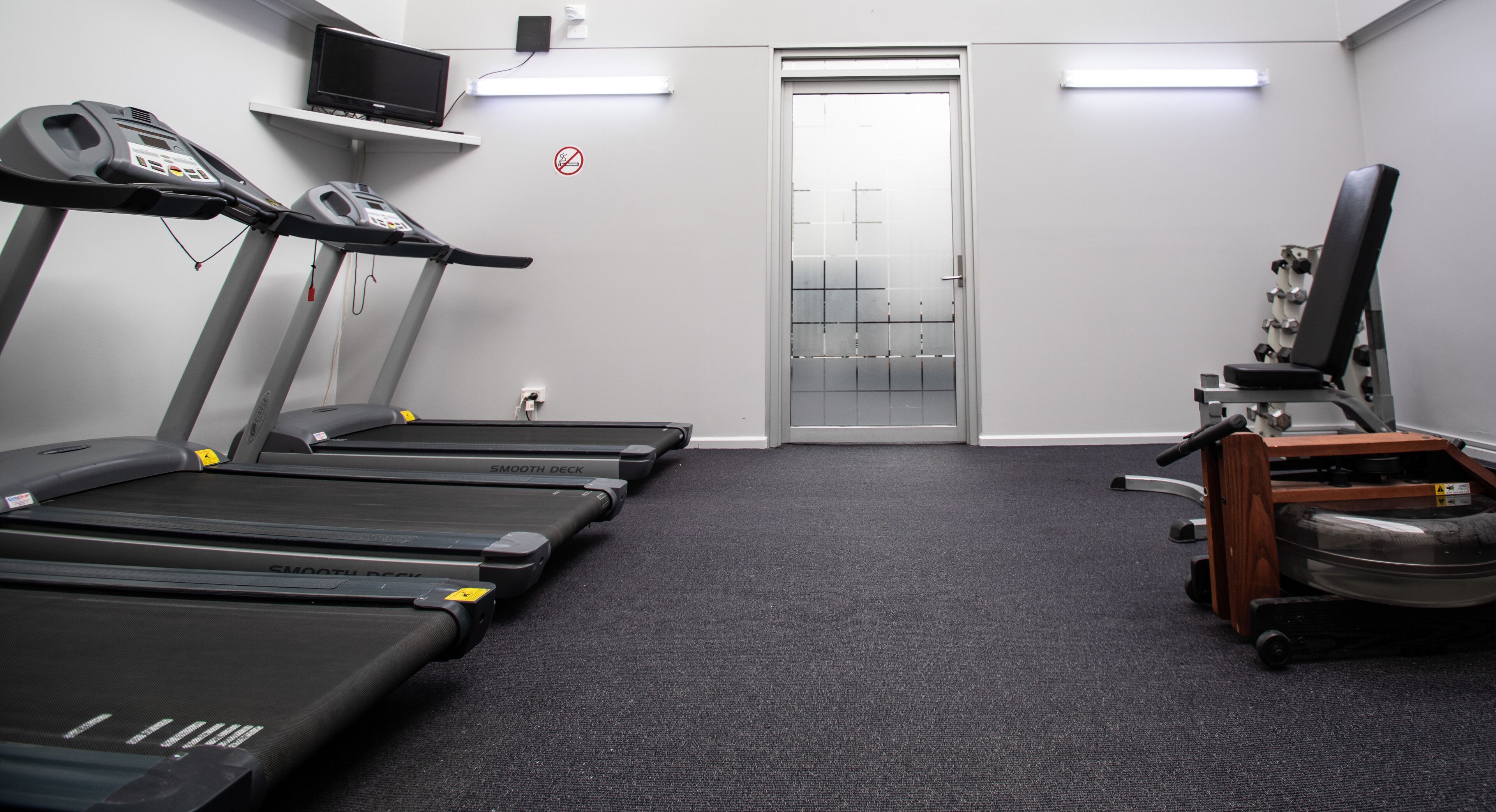 A gym with treadmills, a stationary bike, and a television.