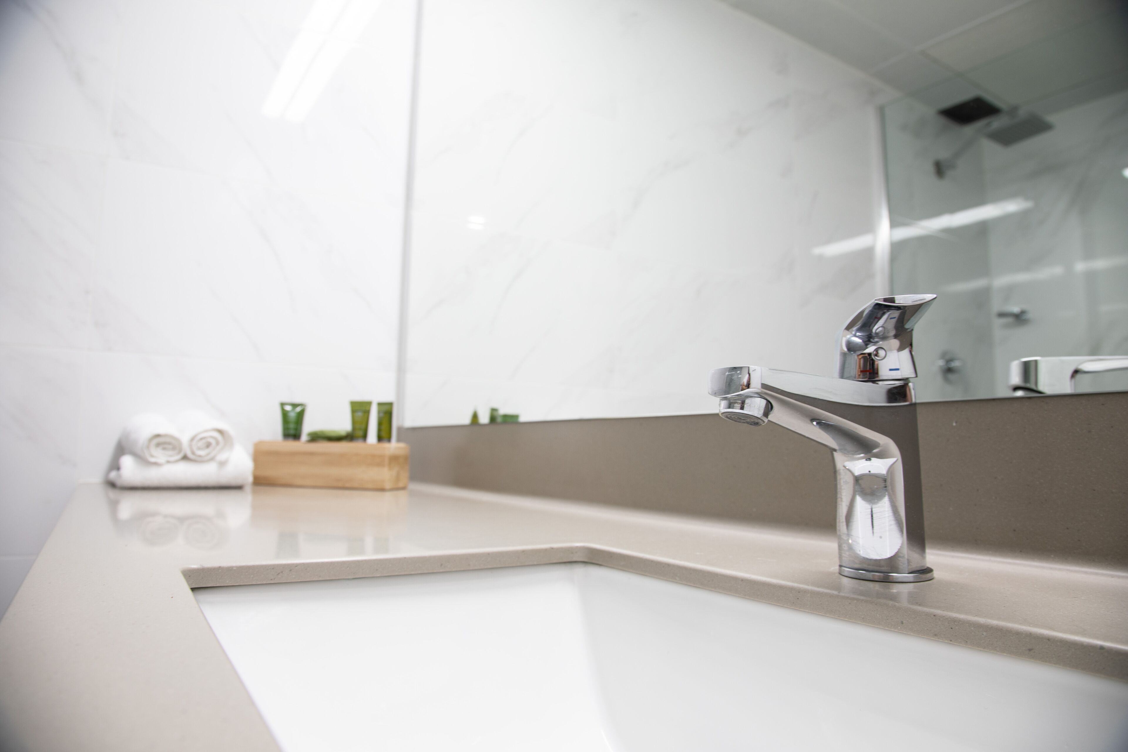 A modern bathroom with a white sink, chrome faucet, and a large mirror.