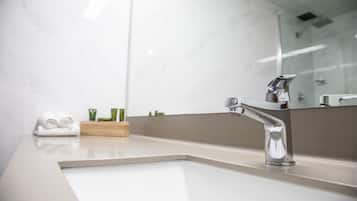 A modern bathroom with a white sink, chrome faucet, and a large mirror.