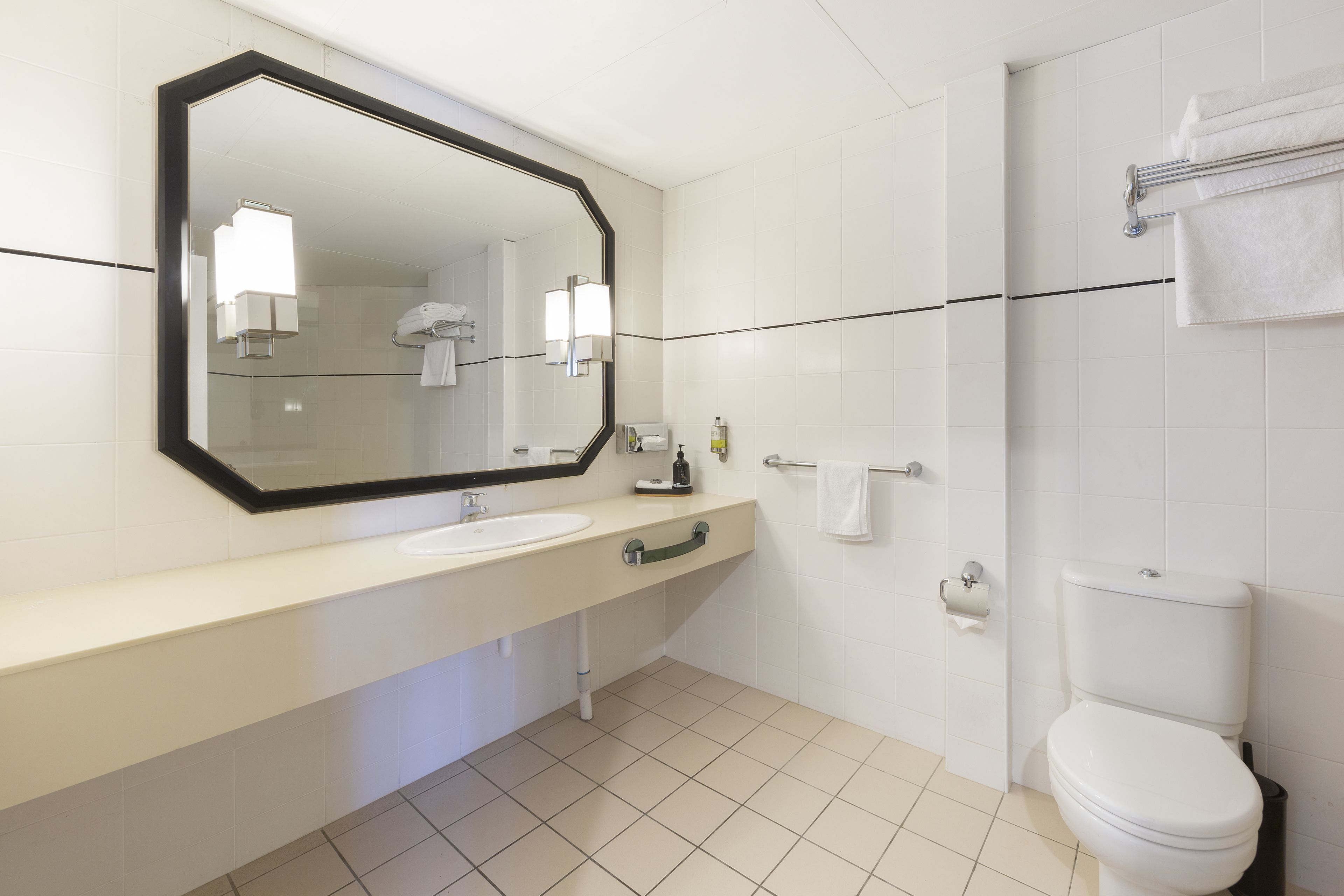 A modern bathroom with a white sink, mirror, and toilet.