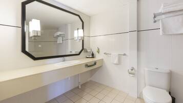 A modern bathroom with a white sink, mirror, and toilet.
