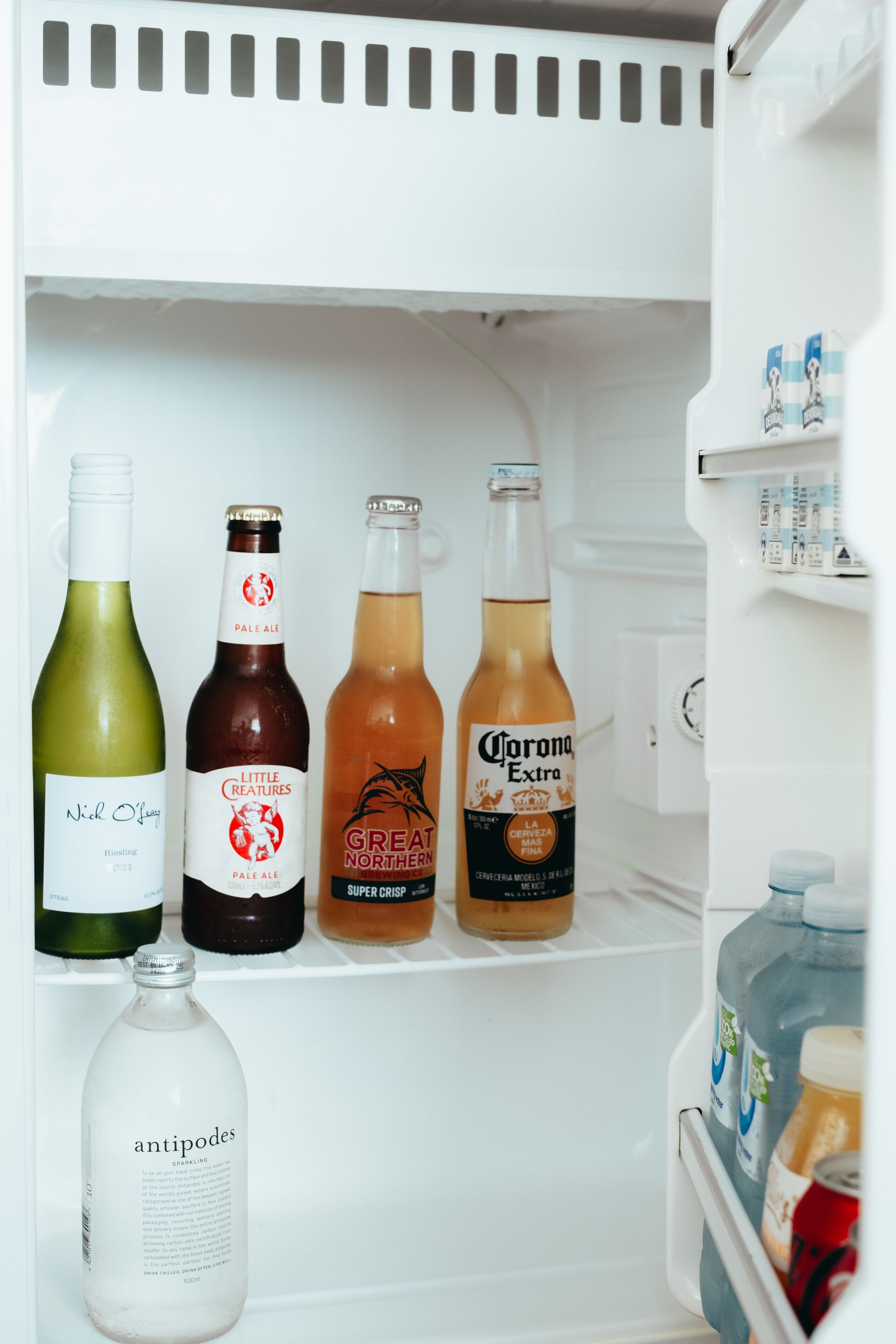 A refrigerator stocked with various beverages including wine, beer, and a bottle of antiproducts.