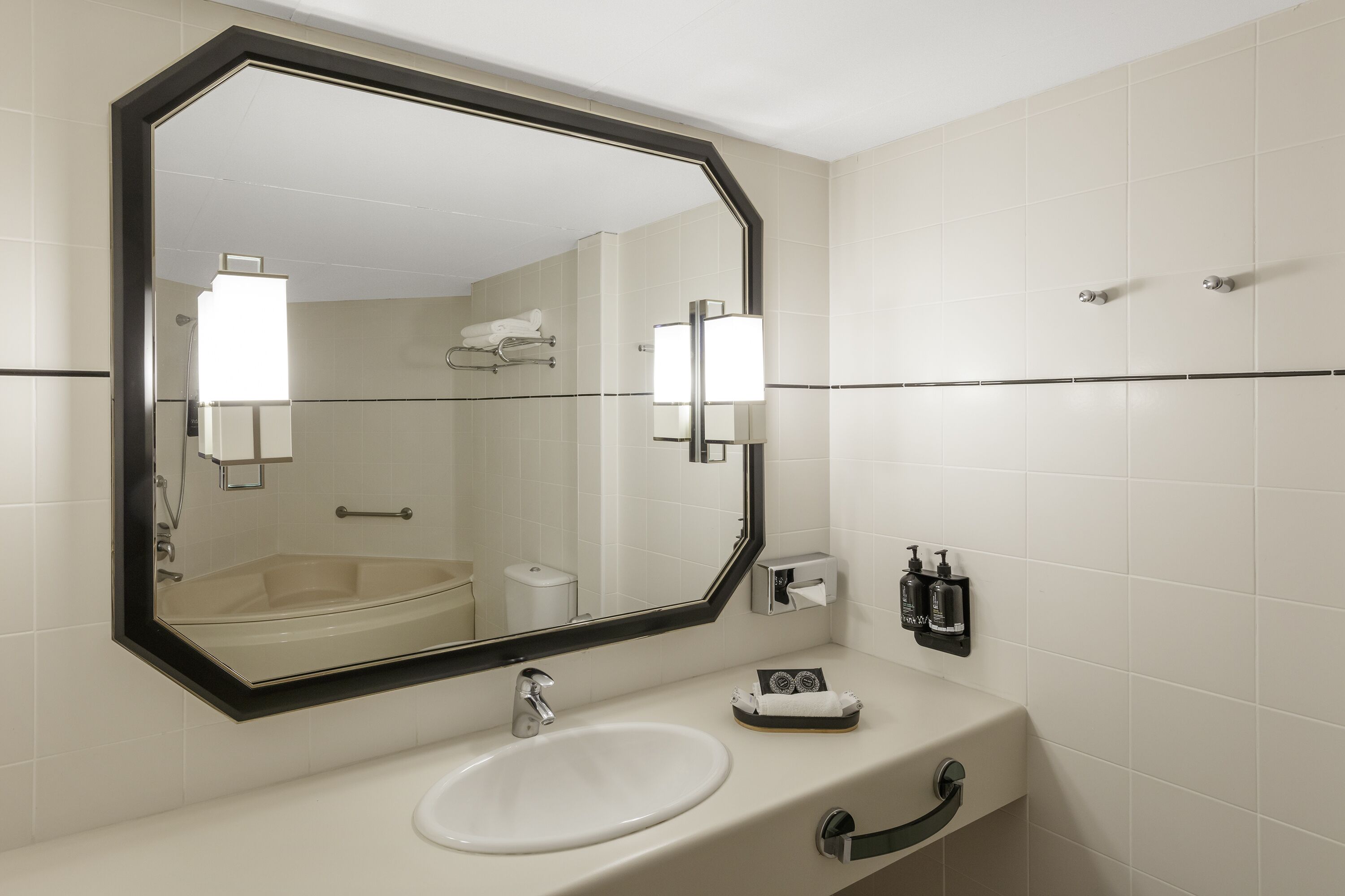 Un bany modern amb un mirall gran, un lavabo i una barra de tovalloles.