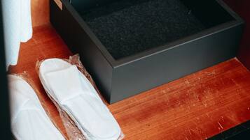 Una caja de almacenamiento con interior negro y exterior de madera, que contiene un par de zapatillas blancas y una caja blanca con la etiqueta 'SHOE SHINE'.