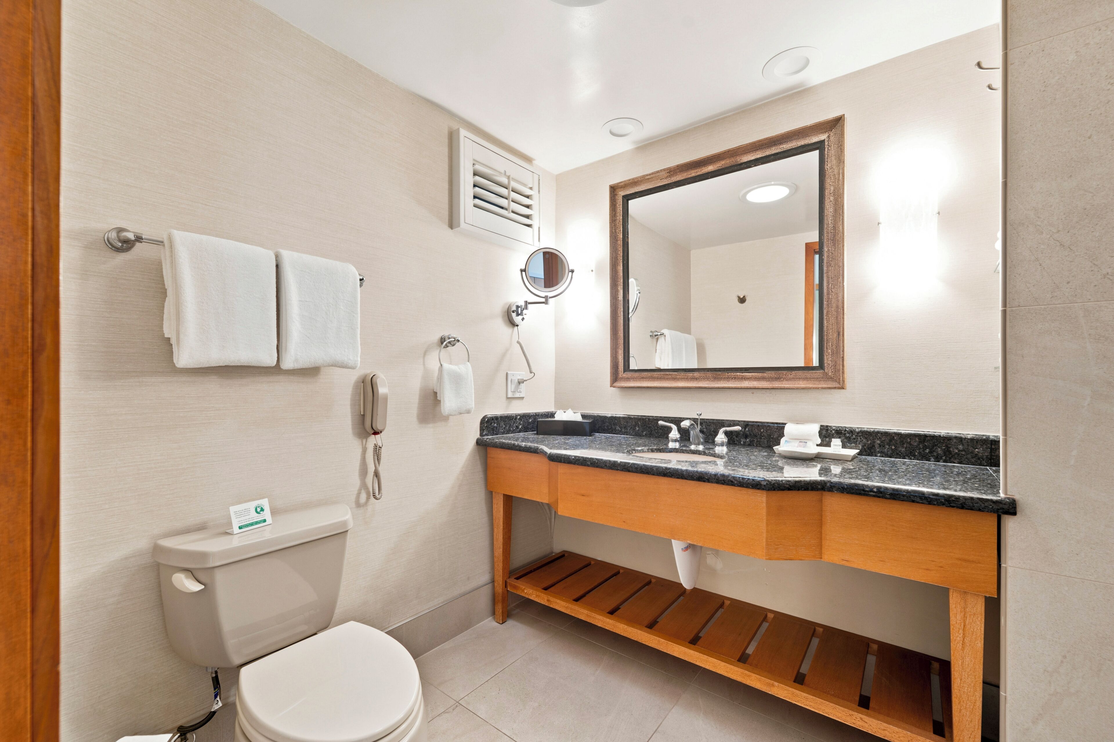 A bathroom with a toilet, sink, mirror, and towel rack.