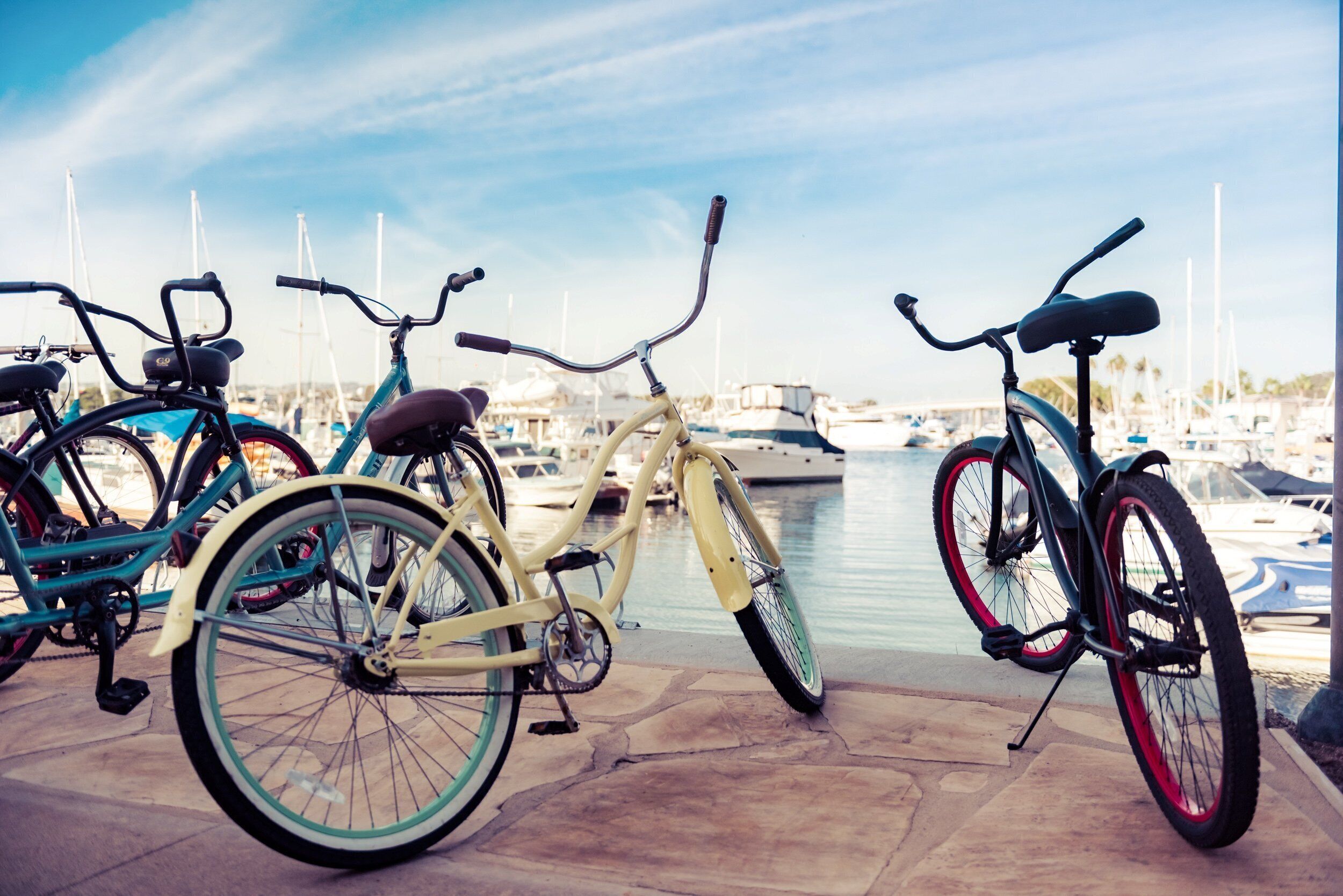 Des vélos sont garés près d’un port de plaisance, avec des bateaux en arrière-plan.