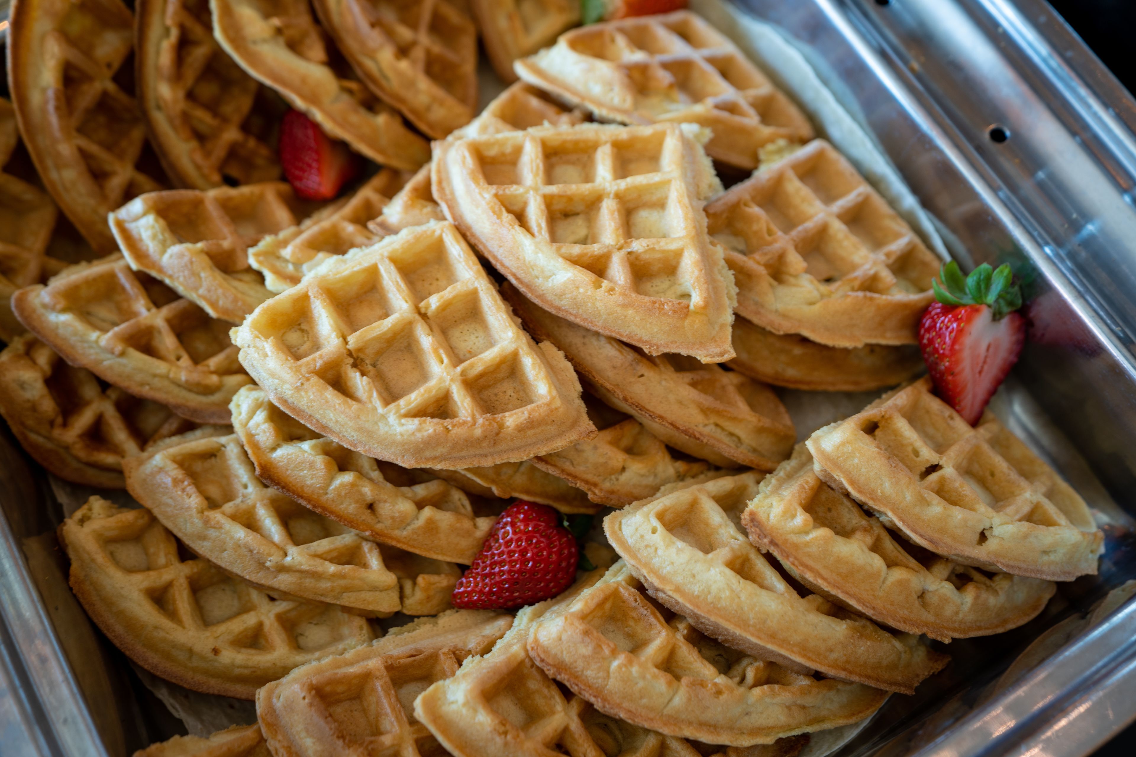 A tray of freshly made waffles with strawberries.