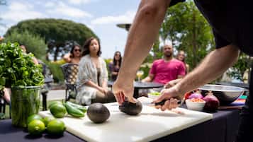 Una persona preparando comida al aire libre, con una tabla de cortar, verduras y un bol.