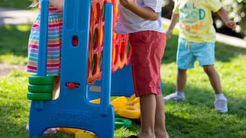 Children playing with a colorful play structure in a grassy area.