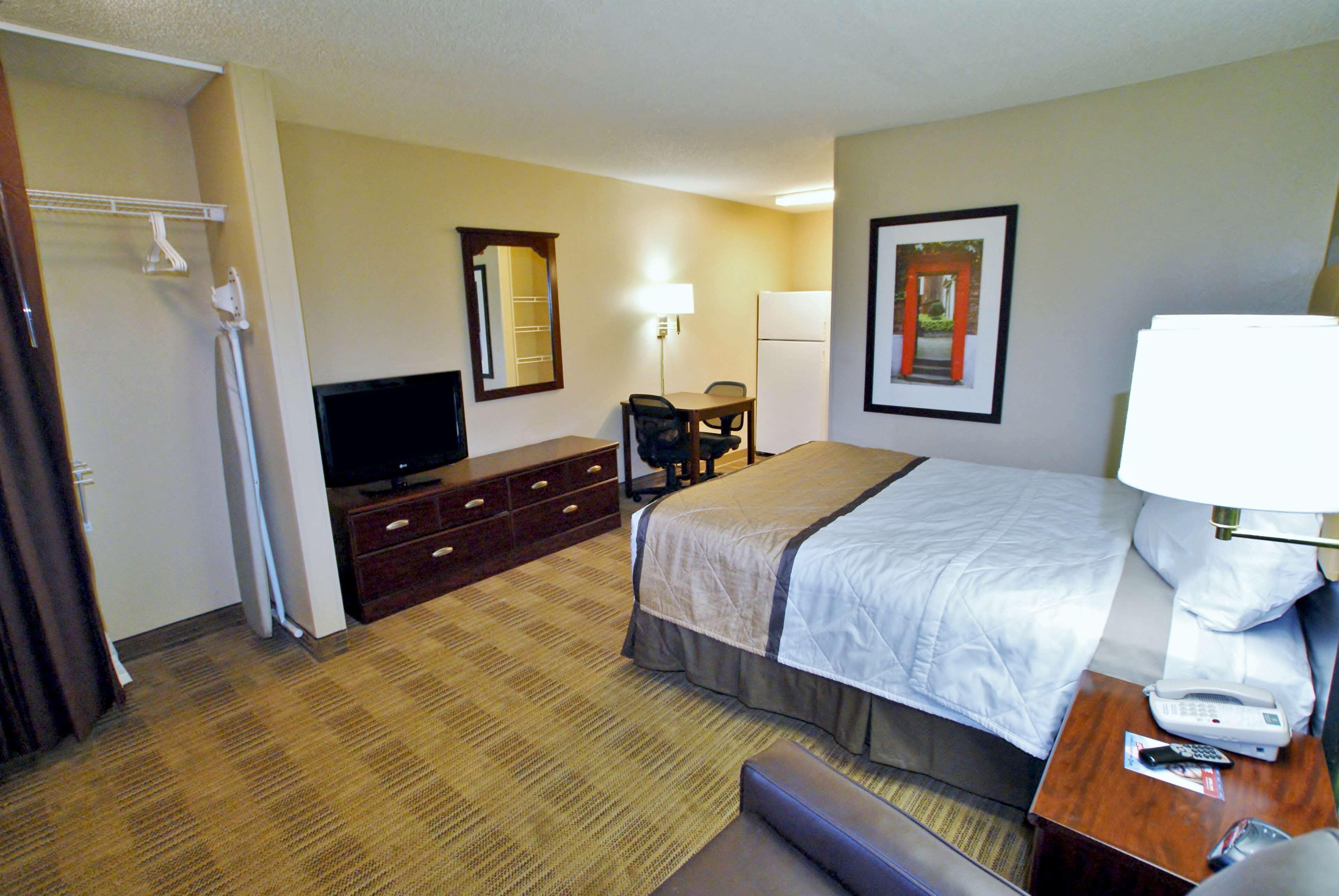 A hotel room with a bed, a desk with a telephone, a chair, a television, and a mirror.