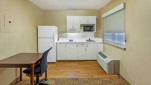 A compact kitchen with white cabinets, a microwave, a refrigerator, and a window with blinds. - Extended Stay America Suites Greensboro Big Tree Way (Greensboro)