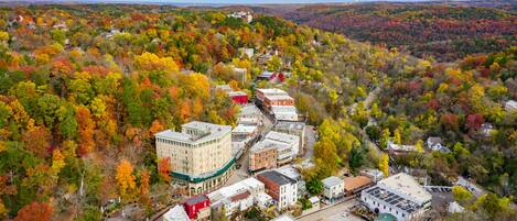 An aerial view of a town with a mix of residential and commercial buildings surrounded by autumn-colored trees.