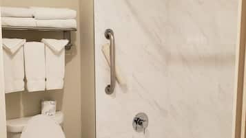 Un bagno con il water, una doccia dotata di maniglione e una vasca da bagno.