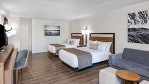 Ein Hotelzimmer mit zwei Betten, einem Schreibtisch, einem Sessel, einer Couch und einem kleinen Tisch.