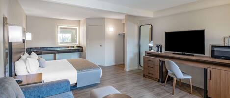 Een moderne hotelkamer met een bed, een bureau, een televisie en een zithoek.