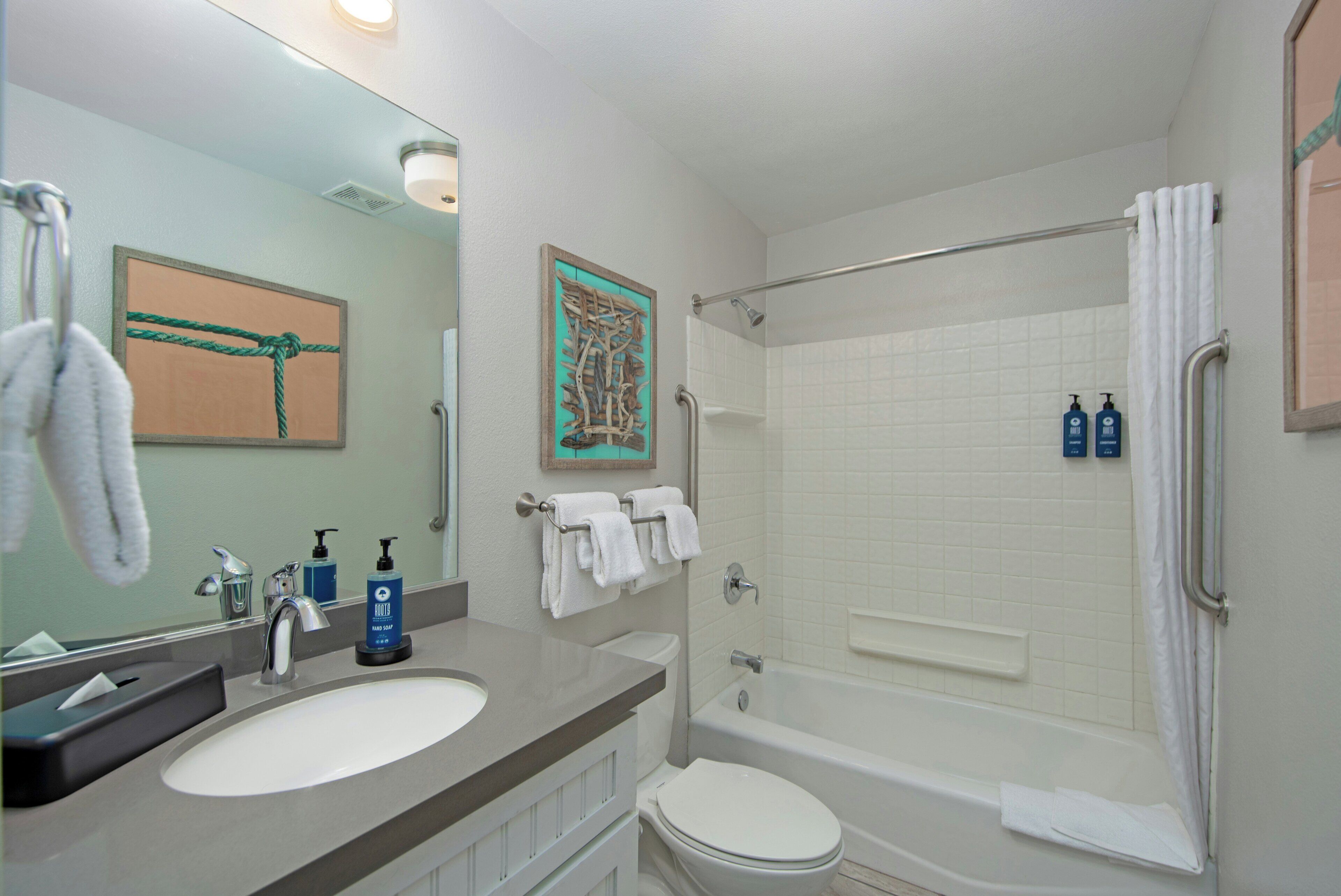 A bathroom with a sink, toilet, bathtub, and a shower area.
