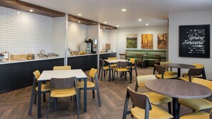A modern restaurant with a brick wall backsplash, wooden herringbone flooring, and a mix of yellow and gray chairs. - Fairfield Inn & Suites by Marriott Scottsdale Old Town (Scottsdale)