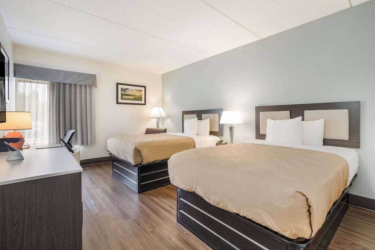 Ein Hotelzimmer mit zwei Betten, einem Schreibtisch und einem Stuhl.
