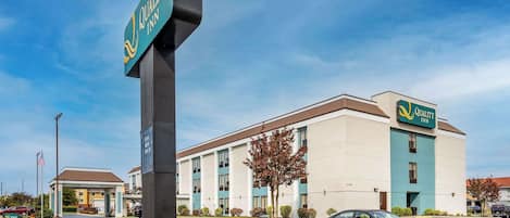A Quality Inn hotel with a prominent sign, a parking lot, and a building with multiple windows and a flat roof.
