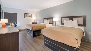 Une chambre d’hôtel avec deux lits, un bureau et une chaise.