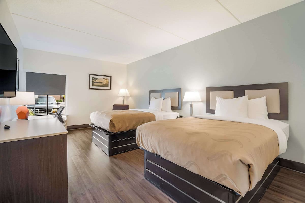Ein Hotelzimmer mit zwei Betten, einem Schreibtisch und einem Fernseher.