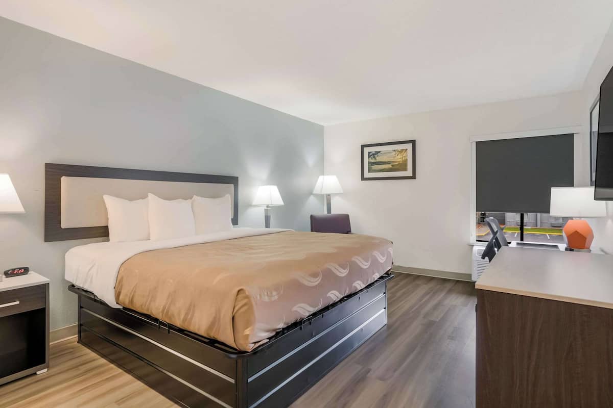 Ein Hotelzimmer mit Bett, Nachttischen, Schreibtisch und Stuhl.