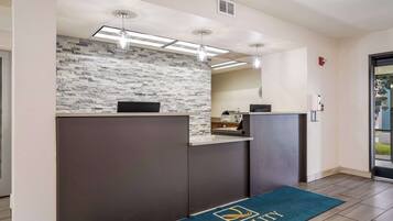 A reception area with a stone wall, a reception desk, and a blue carpet with "Quality Inn" logo.