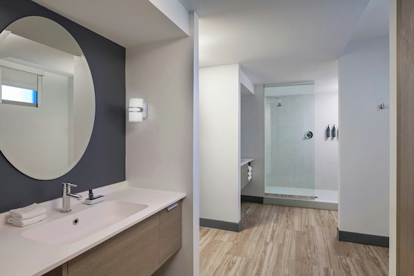 Une salle de bain moderne avec un grand miroir, deux lavabos et un espace douche.