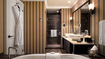 A modern bathroom with a large bathtub, a separate shower area, and a vanity with a sink and mirror.