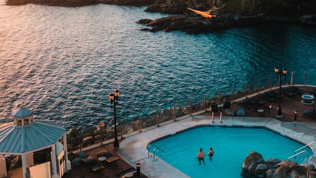 A pool area with lounge chairs and a gazebo, overlooking a body of water and rocky terrain. - Oak Bay Beach Hotel (Victoria)