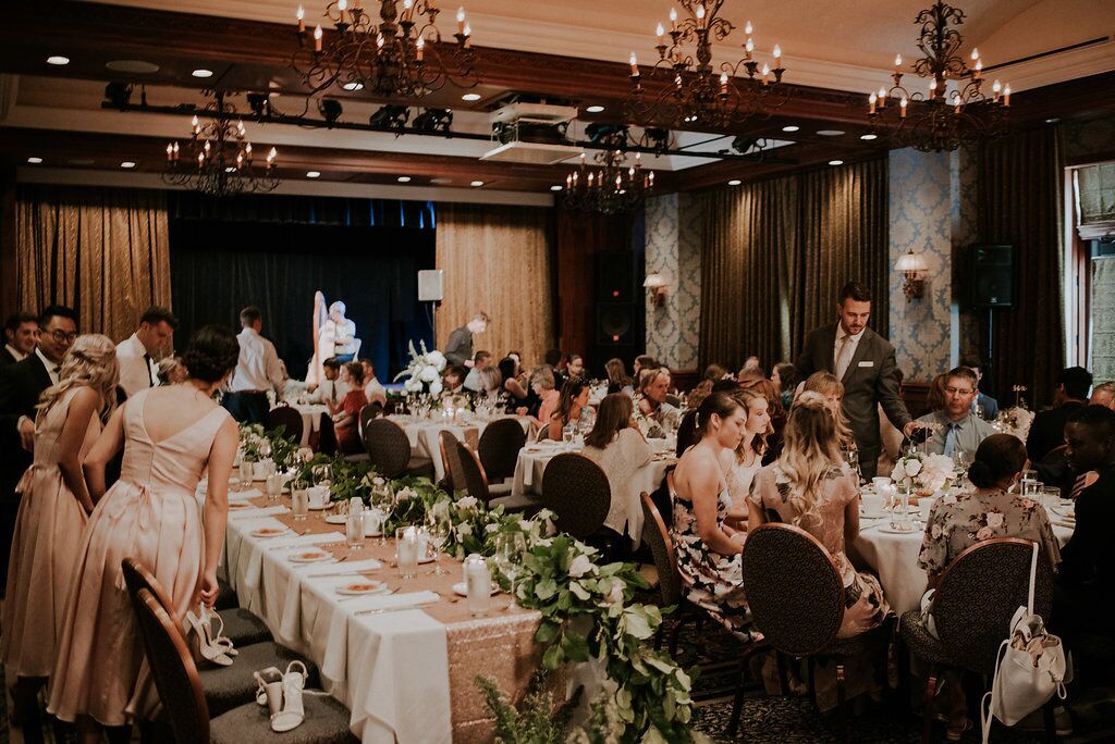 Un salón de banquetes con mesas redondas, candelabros y invitados sentados para un evento formal.