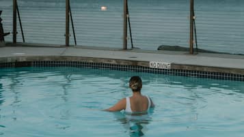 Une piscine avec un panneau indiquant « Il est interdit de plonger », un lampadaire et une vue sur la mer.
