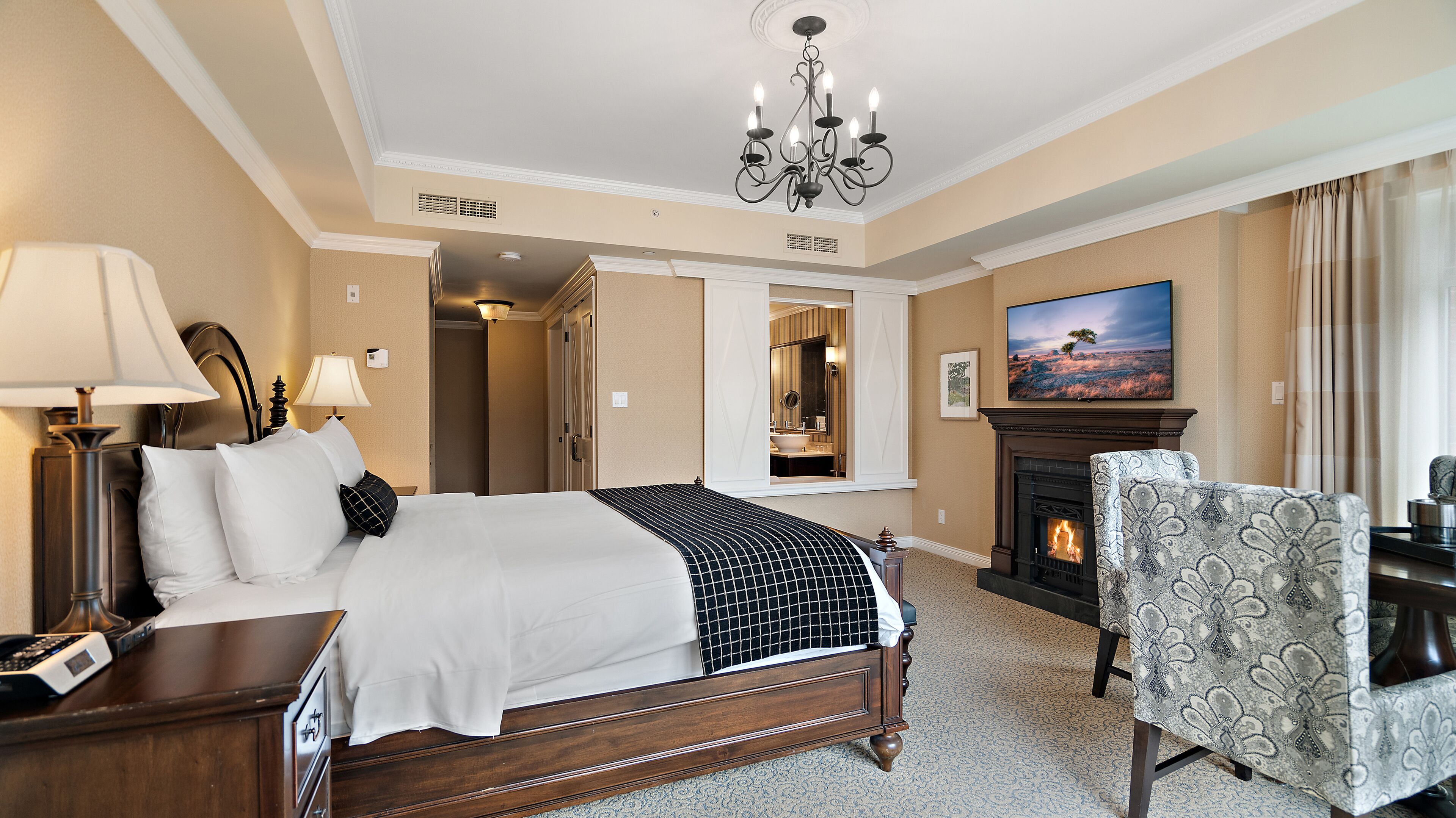 Una habitación de hotel con cama, escritorio, silla, chimenea y televisor.